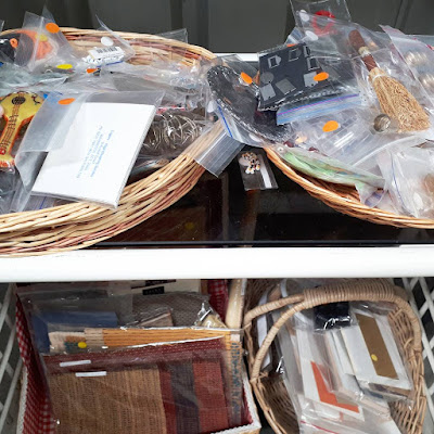 A colse-up view of shelves of baskets holding various craft supplies, with various-coloured stickers on each bag.