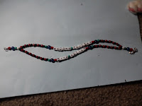 2 stranded bracelet, primarily red and black with accents in silver, green, and blue, that says "making friends with autism"