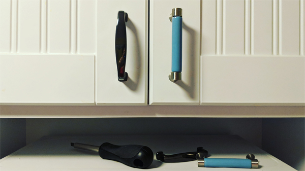 image of cabinet, with one of the new shiny black pulls on the left and one of the old blue plastic and chrome pulls on the right