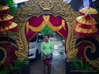 Woman With Balinese Clothes In Front Of Wedding Gate With Lettering Om Swastiastu Means Prayer Safety For All Of Us, Bali, Indonesia