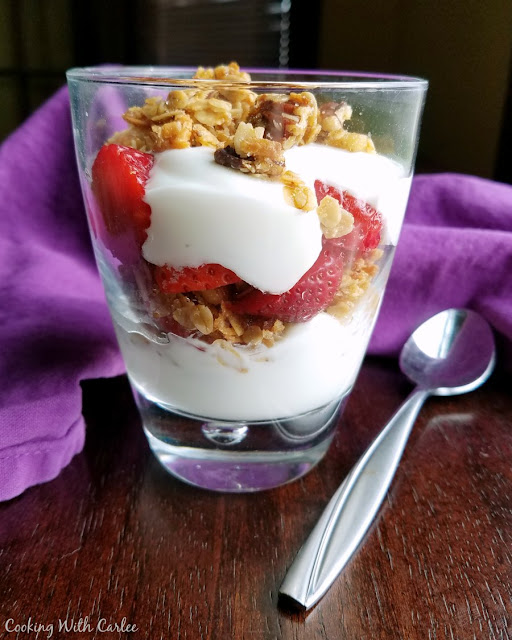 Delicious granola kissed with coconut is so easy to make and makes and excellent breakfast, brunch or light snack. We love it served with fresh berries and yogurt! glass filled with layers of yogurt, granola and strawberries