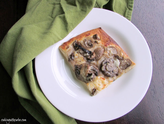 The perfect marriage of garlic, buttery, mushrooms and a flaky crust. MiMi's Mushroom Flatbread is an old family favorite that is always a hit! piece of easy garlic mushroom flatbread on plate