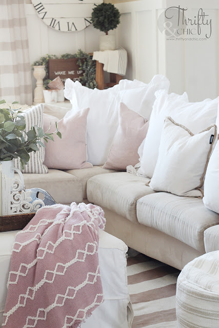 living room with white couch, ottoman, striped rug and pink blanket