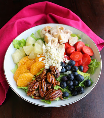 The best part of a salad is always the toppings and this beauty is loaded with the good stuff. All of the fruit, chicken, nuts and cheese go deliciously with the simple to make poppy seed dressing. You will find yourself serving salad a lot more frequently after you try this Portillos inspired chicken and fruit poppy seed salad! big bowl of salad greens topped with pineapple, orange sections, berries, chicken, pecans and cheese