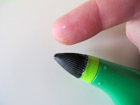 Leaking IDO3D pen next to a finger with blobs of plastic in on it.