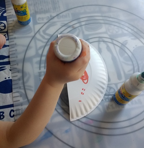 my toddler stamping the paper plate with dot markers