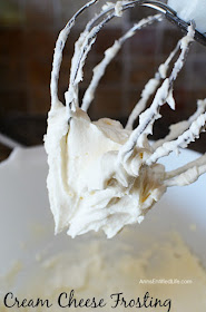 mixer whisk filled with cream cheese frosting