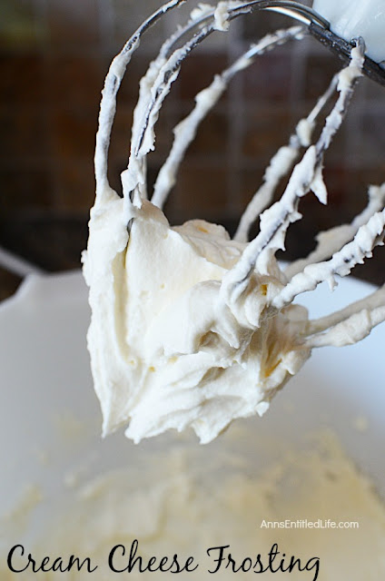 mixer whisk filled with cream cheese frosting