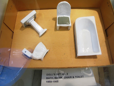 Set of metal dolls' house bathroom furniture displayed in its box.