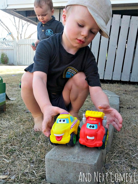 Child driving toy cars along DIY play roads outside