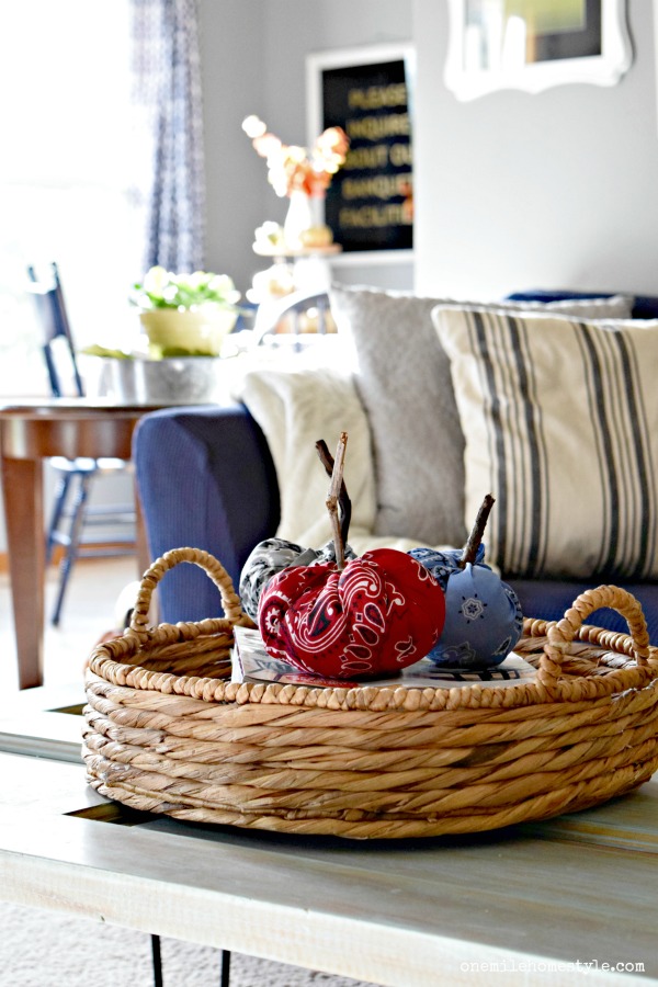 Simple farmhouse coffee table styling with a woven basket and fabric bandana pumpkins