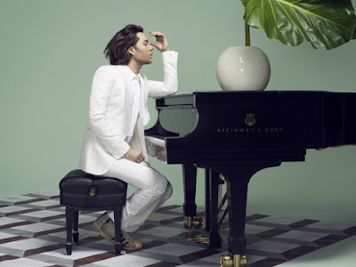 Rufus Wainwright in white suit seated at Steinway piano