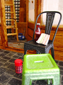Dolls' house miniature builder's lunch on a cafe chair outside the front door of a cafe being renovated.