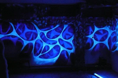 Mlowanie ściany w klubie farbami fluorescencyjnymi, malowidło świecące w ciemności, efekt świecenia ścian