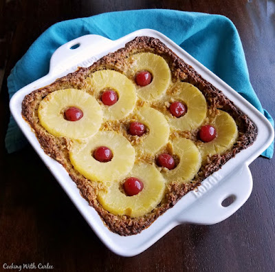 Take a bite of the tropics with this fun breakfast! This baked oatmeal has a great creamy texture but is hearty enough to be cut into pieces. It is just sweet enough to taste like a treat but is a pretty healthy way to start the day! square pan filled with baked oatmeal topped with pineapple and cherries