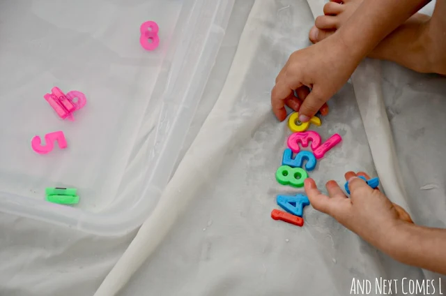 Child lining up colorful plastic number magnets