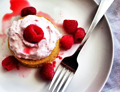 Mini lemon cake with raspberry mousse served on a round, white plate with a fork next to it. 