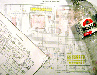 [Image: Papers titled BLOCK DIAGRAM and SCHEMATIC DIAGRAM lying on the table or floor. The schematic diagram is colored in. A bottle of energy drink to the right.]