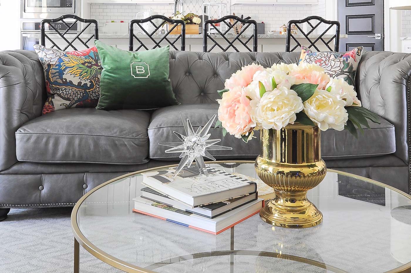 Gray chesterfield sofa with a gold round coffee table and chinoiserie accents. Gray chesterfield sofa with a gold round coffee table and chinoiserie accents.