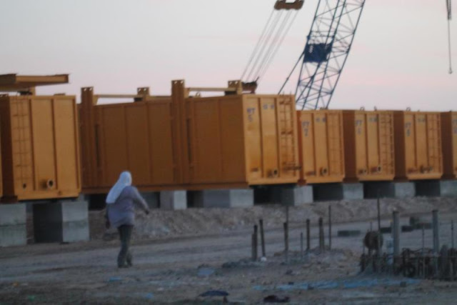 Picture of worker walking by yellow construction trailers on the Kingdom Tower construction site
