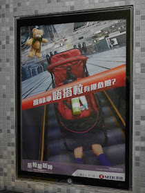 MTR 'No Strollers on Escalators' sign with a teddy bear falling from a great height