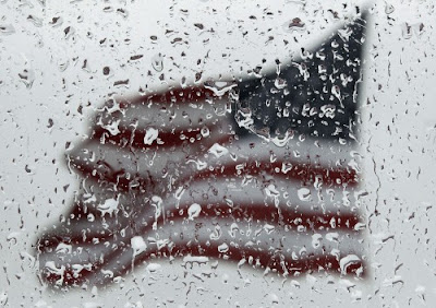 An American flag is seen through rain drops on a window as rain falls in Baltimore, Sunday, April 22, 2012., From ImagesAttr