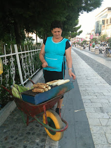 A lady hawker selling corn-cobs on a wheel barrow .