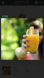 на вытянутой руке женщины стакан лимонного сока и долька лимона закреплена
