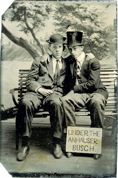 Photo c. 1900s, two young men posing on a park bench with arms around their shoulders, pose with a sign. Under the Anhauser Busch. Jingles and other stories of The American Dream. marchmaton.com Photo c. 1900s, two young men posing on a park bench with arms around their shoulders, pose with a sign. Under the Anhauser Busch. Jingles and other stories of The American Dream. marchmaton.com