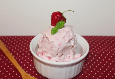 Strawberry basil ice cream topped with a strawberry and basil leaf.
