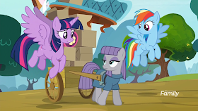 Maud Pie pulling a cart of her sister's possessions as Twilight and Rainbow fly alongside.