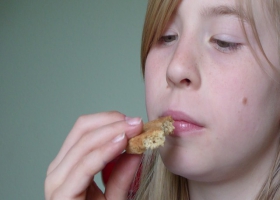 A young lady tastes and smells a cookie. A young lady tastes and smells a cookie.