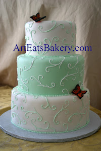 Three tier mint green and white custom unique wedding cake design with curlicues and edible butterf