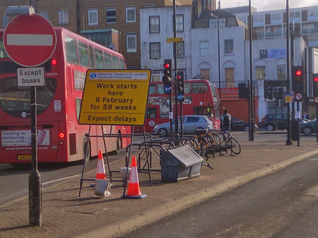 A busy Mile End Road with "expect delays" signage