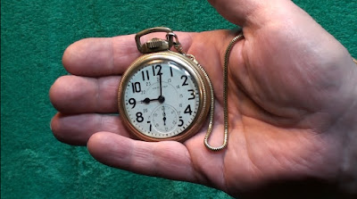Man's hand holding a gold Hamilton trainman's pocketwatch