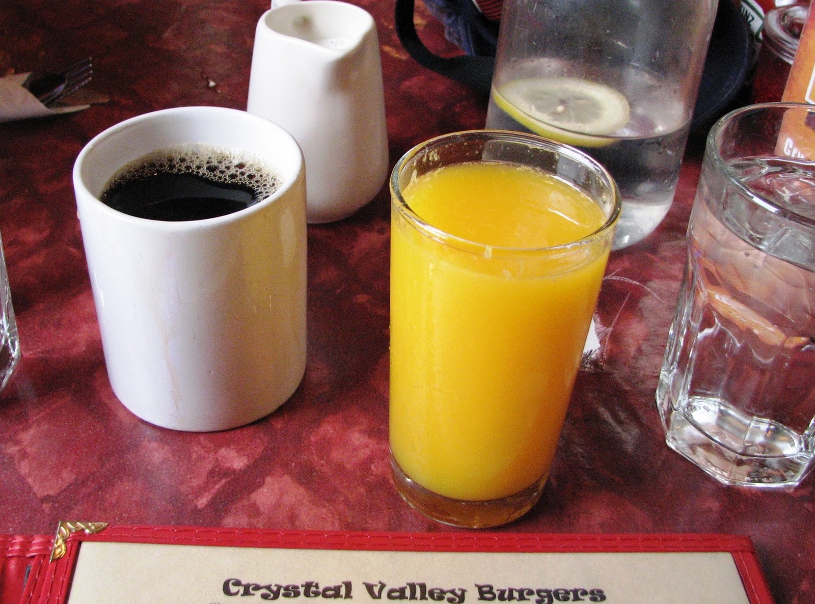 person drinks both coffee and orange juice for breakfast