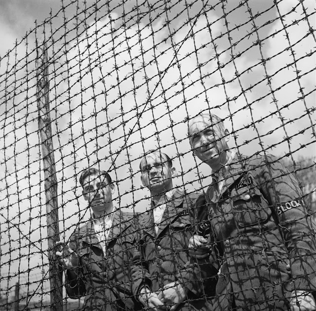 Liberation of the concentration camp Amersfoort. Three Dutch army officers behind barbed wire. From the collection of the Nationaal Archief of the Netherlands.