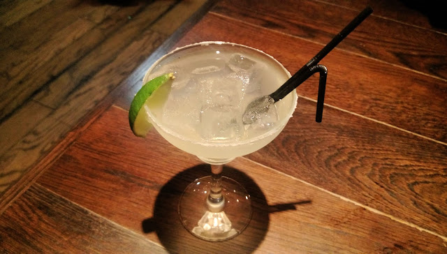 A glass containing a Margarita, with a slice of lime on the side. 