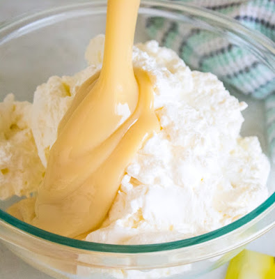 pouring sweetened condensed milk over whipped cream for no churn ice cream