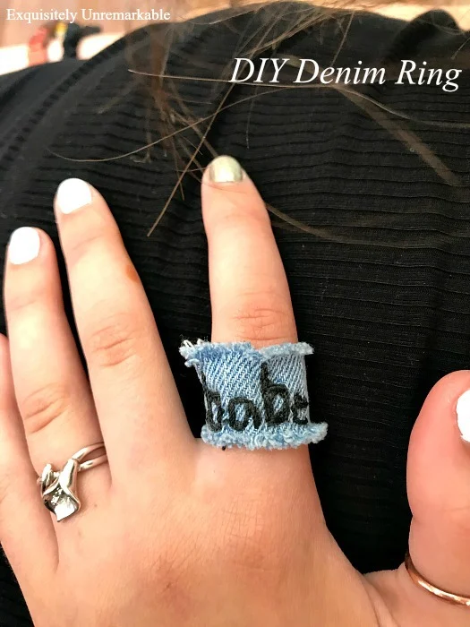 Babe embroidered on denim ring shown on hand with other rings