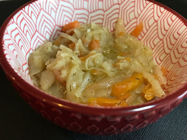 A red patterned bowl with shredded cabbage and carrots in a liquid