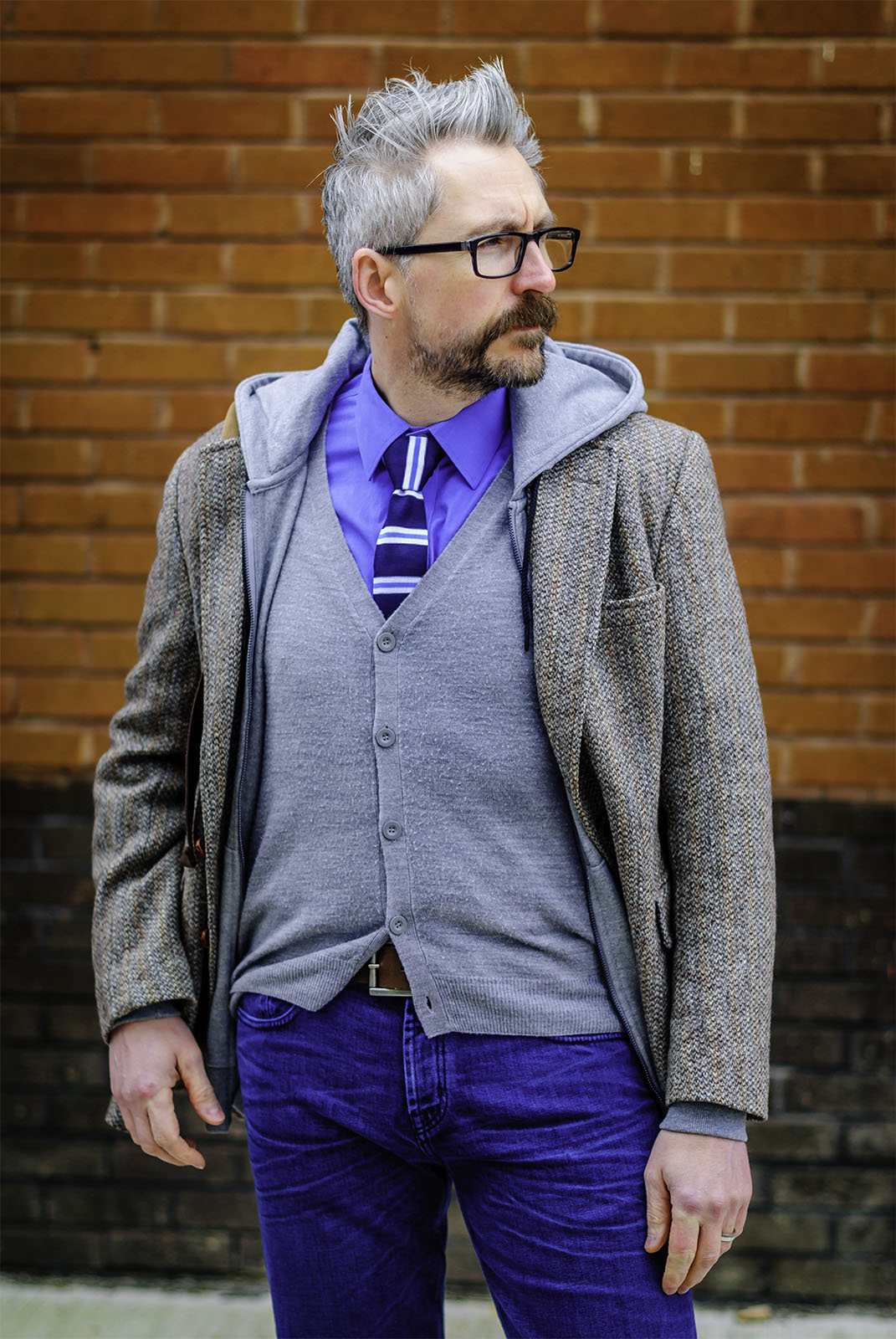 A layered smart casual outfit: Striped tie \ dress shirt \ grey cardigan \ grey hoodie \ Harris tweed jacket \ jeans \ grey brogues | Silver Londoner, over 40 menswear