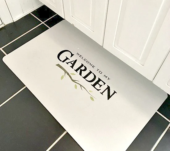 white bathroom mat with Garden stenciled on it