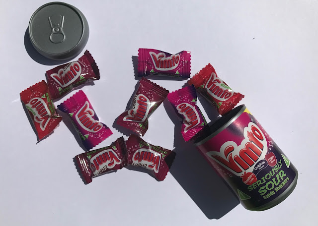 A plastic tub with individually wrapped Vimto sweet packets spilling out