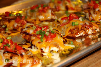 Thinly sliced or pounded pieces of boneless chicken breast are grilled, then topped with barbecue sauce, bacon and shredded cheeses, and finished with a garnish of fresh chopped tomatoes and sliced green onion.