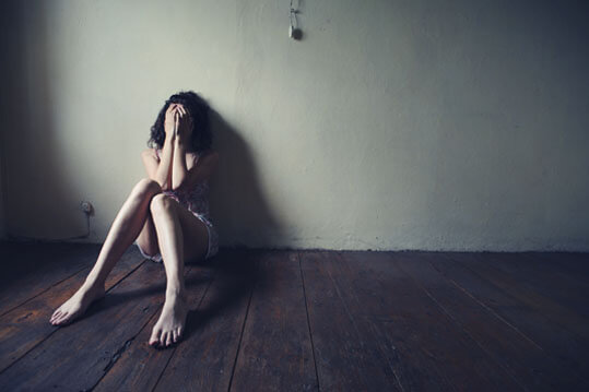 Persona depresiva sentada en el fondo de un cuarto vacio
