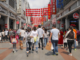 people, including a few wearing face masks, at the Shangxiajiu Pedestrian Street