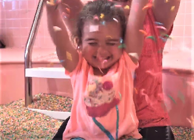 A toddler plays in colorful sprinkles