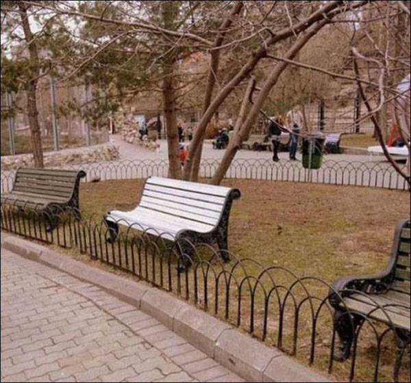 sillas en un parque con una reja que impide sentarse