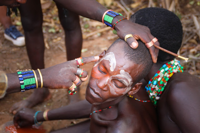 a bena tribe boy getting his face painted during a bull-jumping ceremony in omo valley, ethiopia